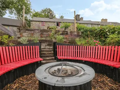 two red chairs and a fire pit in a yard at Bwthyn Dyfi in Machynlleth