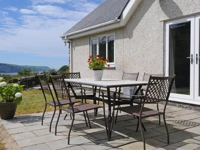 a table and chairs on a patio with a house at Bryn Derw in Barmouth