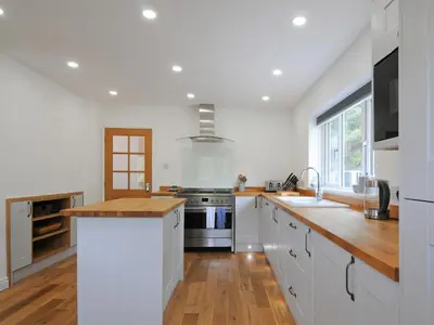 a kitchen with white cabinets and a wooden counter top at Bryn Derw in Barmouth