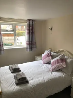 a bedroom with a white bed with pink and white pillows at 9 Bromleys Court in Church Stretton