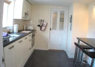 a kitchen with white cabinets and a white door at 9 Bromleys Court in Church Stretton