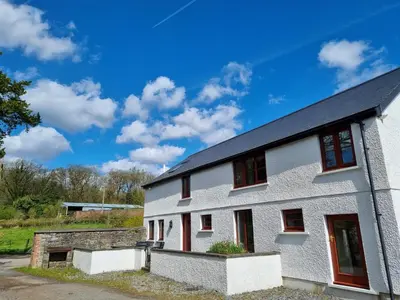 a white house with red windows and a blue sky at Kestrel Farmhouse in Llandovery