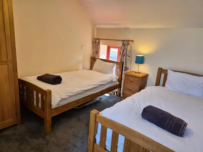 a bedroom with two beds and a lamp on a table at Kestrel Farmhouse in Llandovery