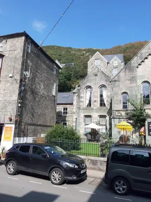 two cars parked on a street in front of a building at Ground Floor Barmouth Centre Apartment With Garden in Barmouth