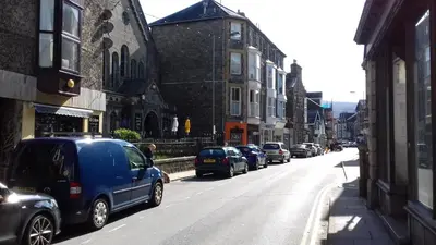 a blue van parked on the side of a city street at Ground Floor Barmouth Centre Apartment With Garden in Barmouth