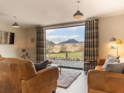 a living room with couches and a large window at Cartref in Trawsfynydd