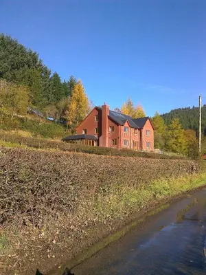 a large red brick house on a hill next to a field at Laurel Bank in Abbey-Cwmhir