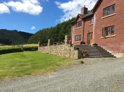 a brick house with a stone wall and stairs at Laurel Bank in Abbey-Cwmhir