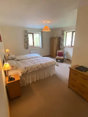 a bedroom with a bed and a dresser and two windows at Laurel Bank in Abbey-Cwmhir