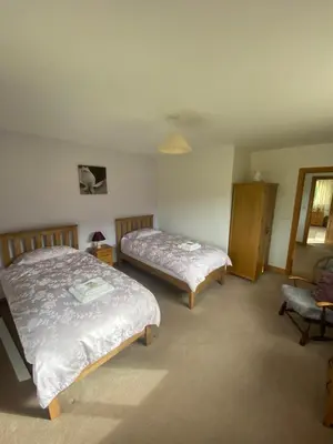 a bedroom with two beds and a chair at Laurel Bank in Abbey-Cwmhir