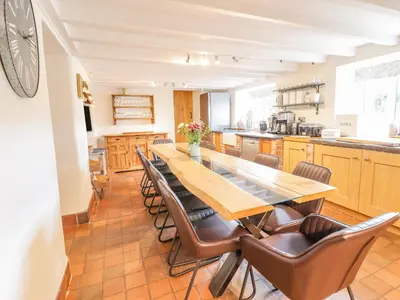 a kitchen with a long wooden table and chairs at Cefn Nannau in Corwen