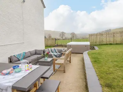 a patio with a couch and a table in a yard at Cefn Nannau in Corwen