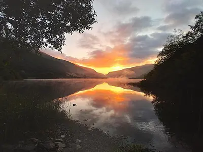 a sunset over a body of water with the sky at Pen-Y-Bont Hotel in Tal-y-llyn