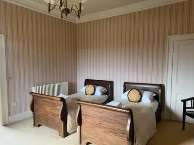 a bedroom with two beds and a chandelier at Netley Hall in Shrewsbury
