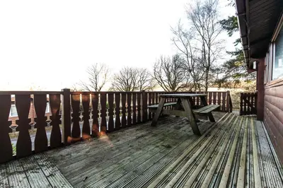 a wooden deck with a picnic table on it at Rustic Log cabin in Snowdonia By Seren Short Stays in Trawsfynydd
