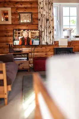 a living room with a tv on a wooden wall at Log Cabin nr Coed y brenin By Seren Short Stays in Trawsfynydd