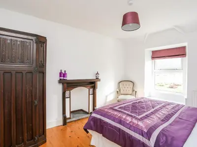 a bedroom with a bed and a table and a window at Glyn Morfa in Harlech