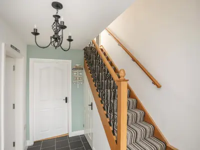 a staircase in a home with a chandelier at Red Ridge in Harlech