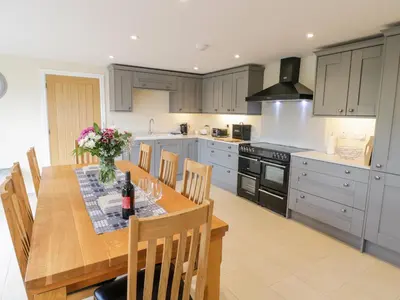 a kitchen with a wooden table with chairs and a kitchen withuclear at Bryn Mawndy in Corwen