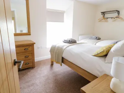 a bedroom with a bed and a dresser and a mirror at Bryn Mawndy in Corwen