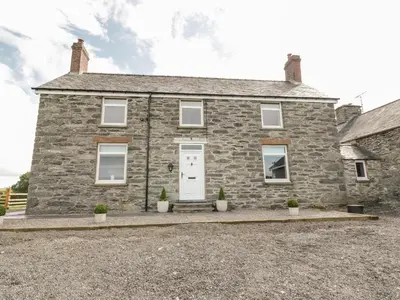 a stone house with a white door and potted plants at Bryn Mawndy in Corwen