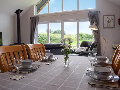 a dining room table with a vase of flowers on it at Bumble Lodge in Llynclys