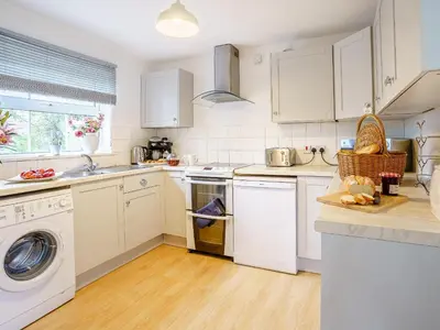a kitchen with white cabinets and a washer and dryer at Fron Towyn Cottage in New Quay
