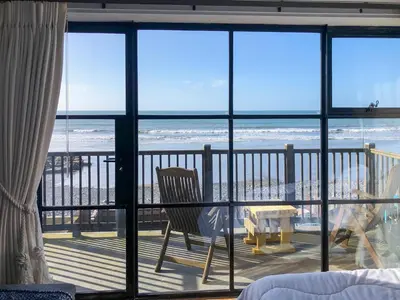 a room with a balcony with a view of the beach at Ystwyth House in Borth