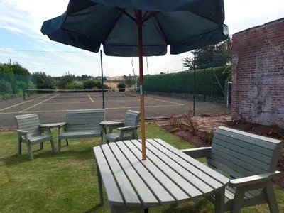 a picnic table with an umbrella on a tennis court at Upper Eyton Farmhouse B&B in Shrewsbury