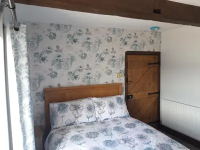 a bedroom with a bed with blue flowers on the wall at Upper Eyton Farmhouse B&B in Shrewsbury