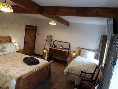 a bedroom with two beds and a desk and a mirror at Upper Eyton Farmhouse B&B in Shrewsbury