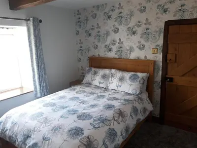 a bedroom with a bed with a blue and white comforter at Upper Eyton Farmhouse B&B in Shrewsbury