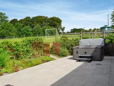 a garden with a hot tub and a bench on a patio at Caffi Sali - Weluk143 in Blaenpenal