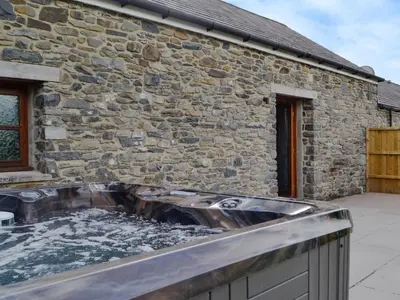 a hot tub in front of a stone building at Caffi Sali - Weluk143 in Blaenpenal