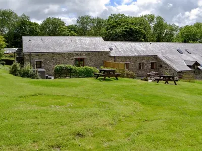 a stone barn with picnic tables in front of it at Caffi Sali - Weluk143 in Blaenpenal