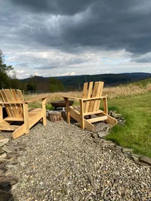 two wooden chairs and a picnic table in a field at Belan Bluebell Woods Shepherds Hut in Llanidloes