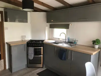 a kitchen with gray cabinets and a sink and a stove at 8F Lakeside Lodge Caer Beris Builth Wells - No Tradesman in Builth Wells