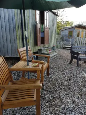 a patio with two wooden chairs and an umbrella at Cornflour Cozy Cabin Retreat in Craven Arms