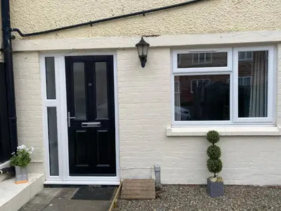 a house with a black door and two windows at 10 Bromleys Court in Church Stretton