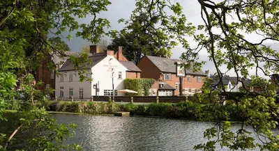 a large white house next to a river at Ye Old Boote Inn in Whittington