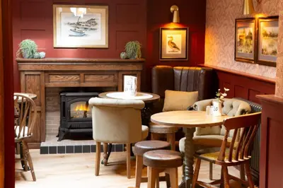 a restaurant with a fireplace and two tables and chairs at Ye Old Boote Inn in Whittington