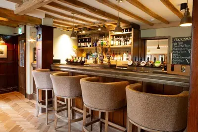 a bar with a row of bar stools at Ye Old Boote Inn in Whittington