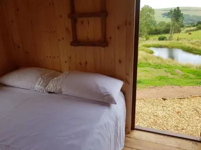 a bed in a wooden room with a window at Cozy Cabin Retreat - Sleeps 2 & a Child in Craven Arms