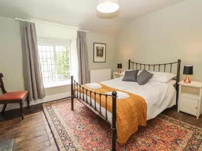 a bedroom with a bed and a rug at Cwmalis Hall in Llangollen