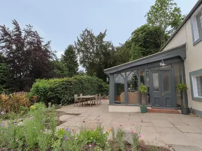 a conservatory with a table in a garden at Cwmalis Hall in Llangollen