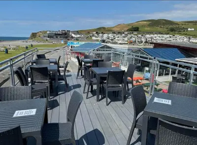 a deck with tables and chairs and the ocean at Hill View caravans in Aberystwyth