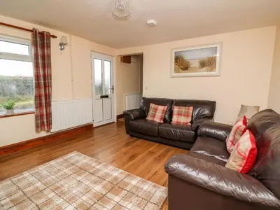 a living room with a leather couch and a rug at Green Cottage in Rhayader