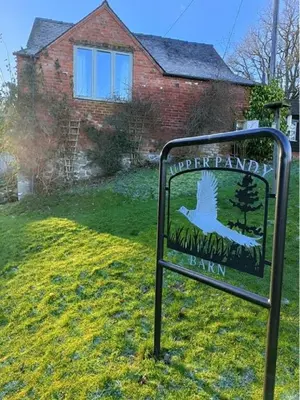 a sign in the grass in front of a house at Pandy Barn Berriew in Welshpool