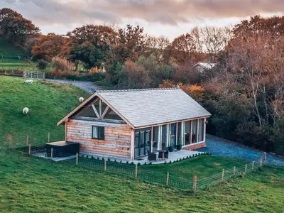 a small log cabin in a field with a fence at Oak View in Highgate