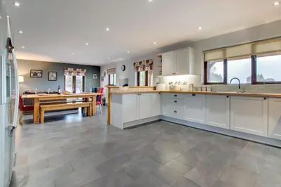 a large kitchen with white cabinets and a dining table at 3 Bed in Bala oc-bow162 in Bala